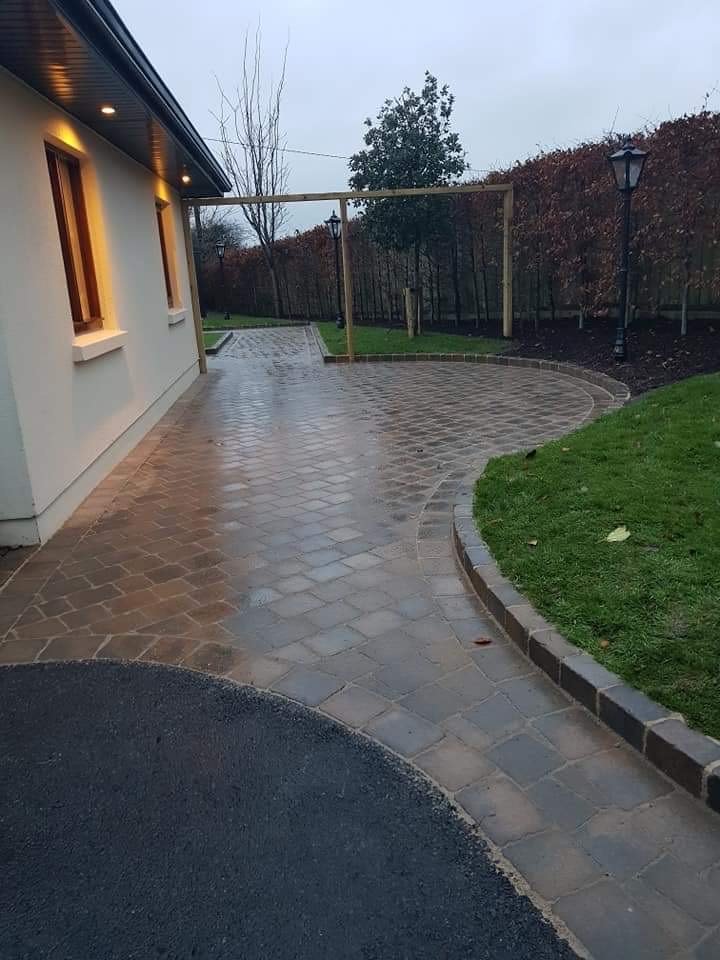 Curved block paved driveway and path beside lawn and mature boundary planting