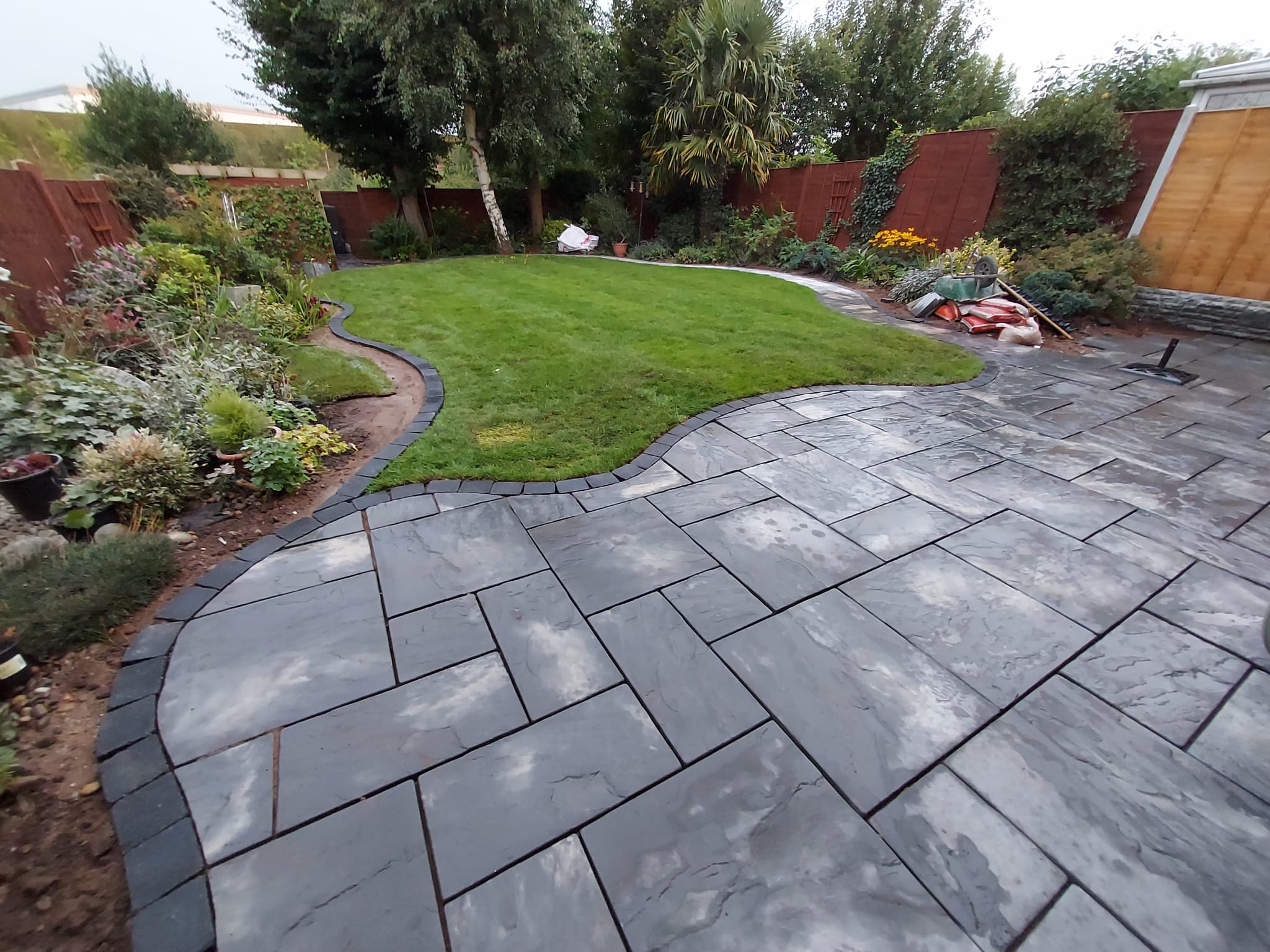 Dark stone garden paving around a curved lawn in Lichfield
