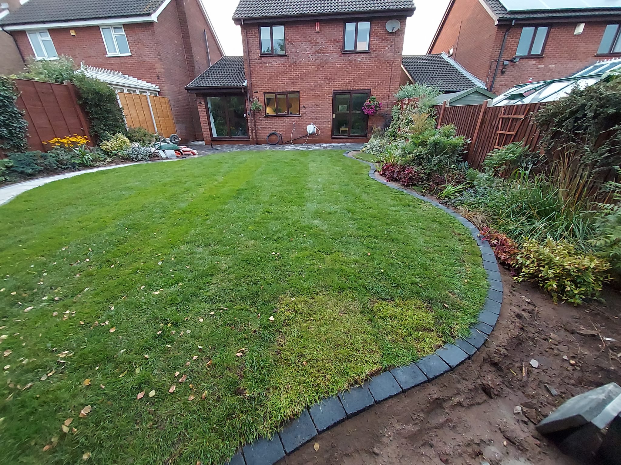 Curved lawn and paved border in a completed Lichfield garden