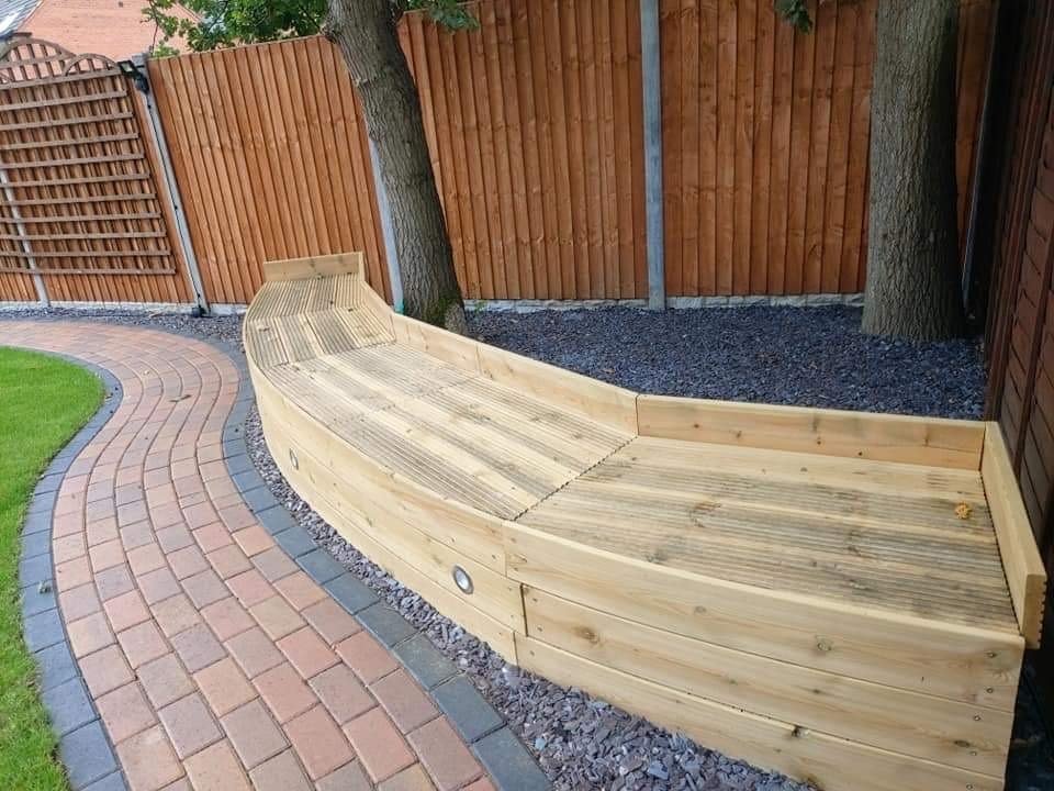 Curved timber sleeper seating beside a block paved garden path